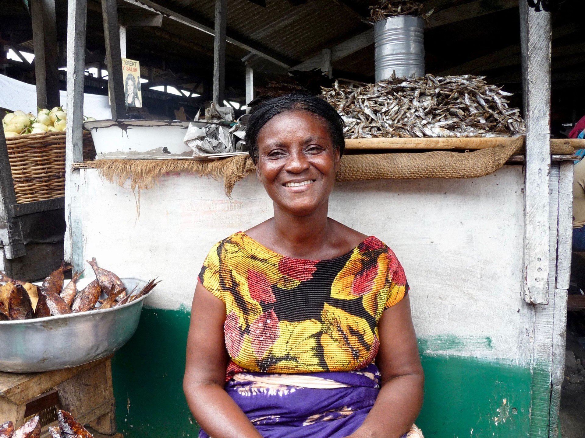 Portrait d’une femme souriante assise près des fruits de mer au marché